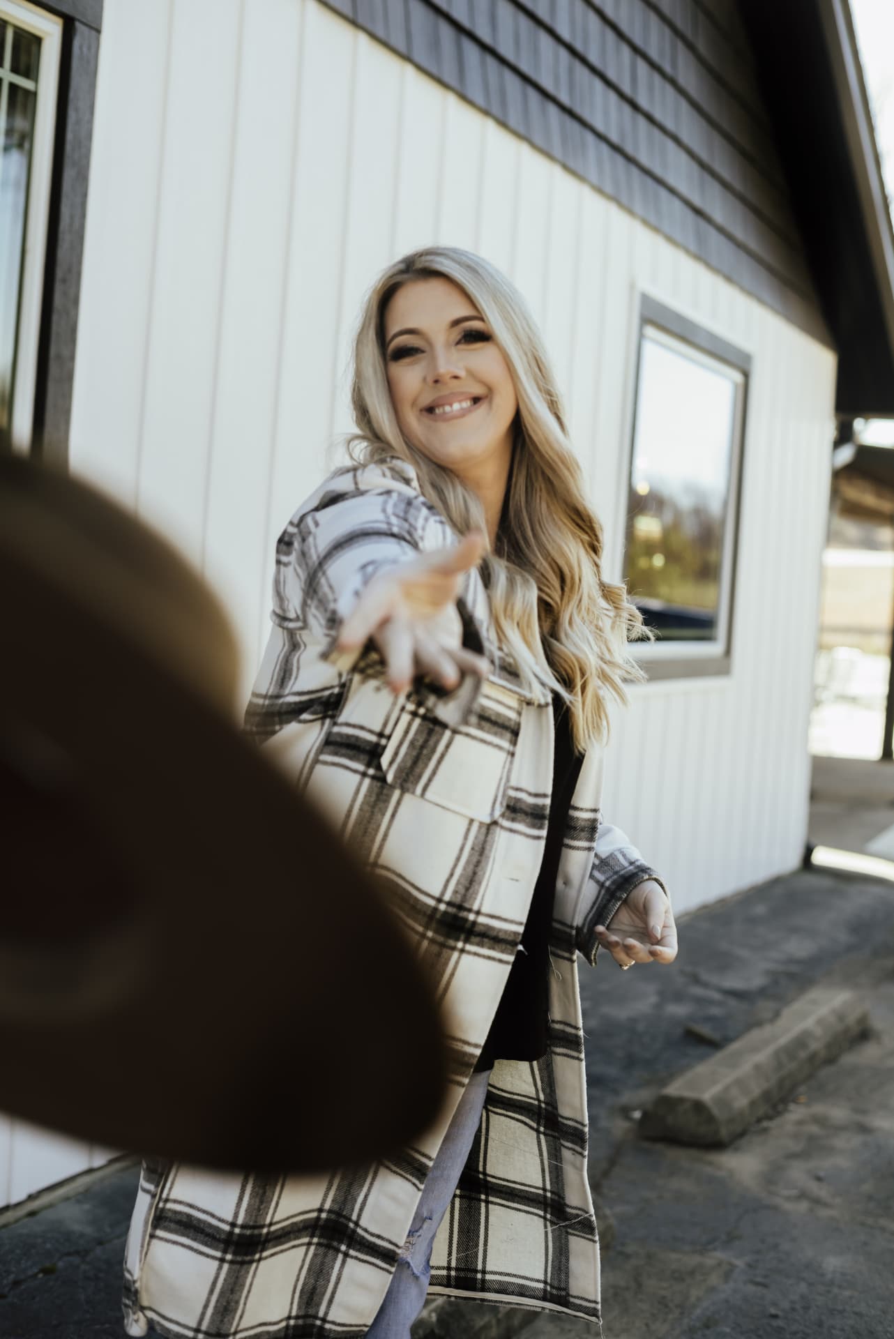 Candace Roberts reaching out a hand in a plaid coat